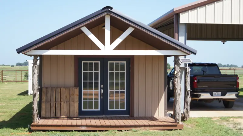 Wood cabin building beside a covered carport on the ranch grounds