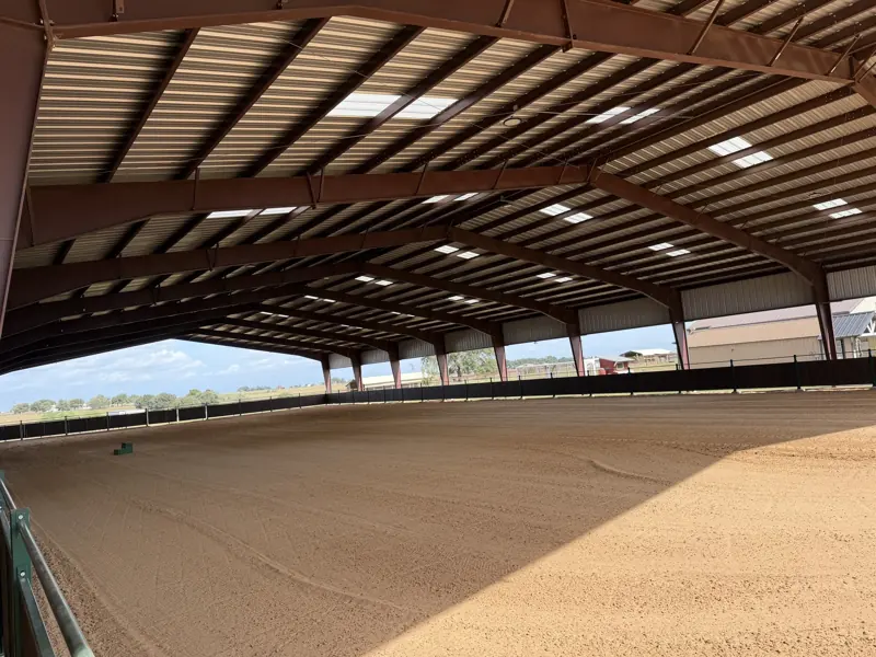 Wide view of the covered arena with sand footing and open sides