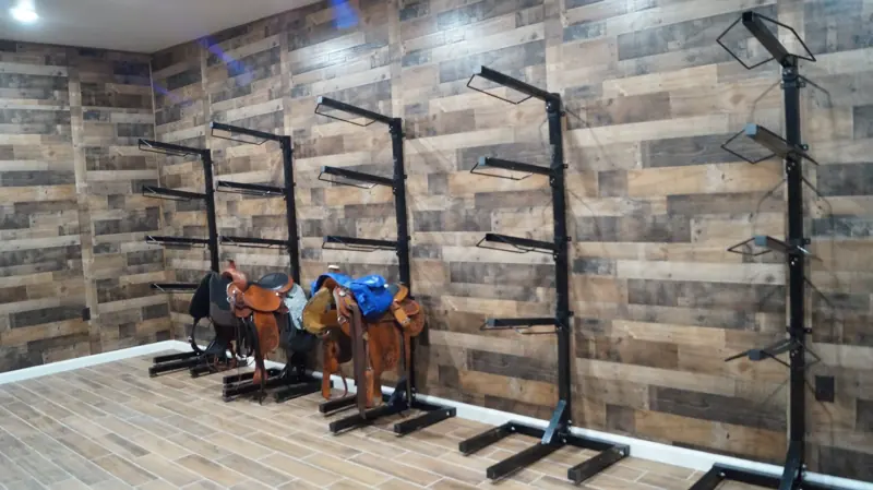 Heated and air-conditioned tack room with saddle racks and wood-plank walls